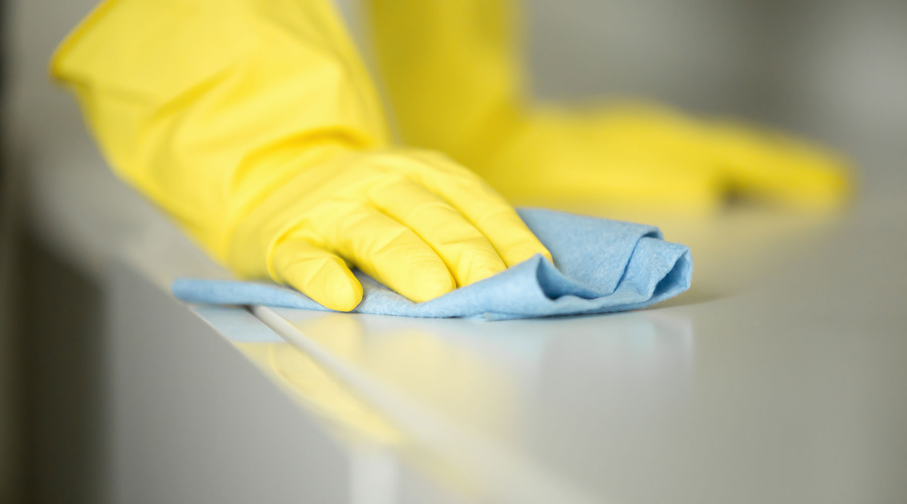 Gloved hands sanitizing a surface